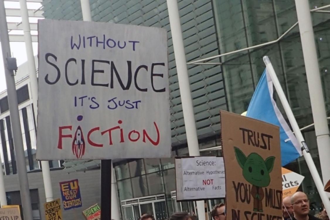 Cardboard sign that says 'without science it's just fiction"