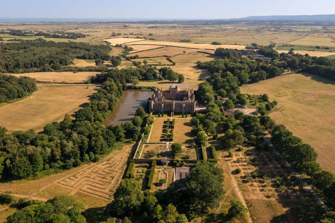 Birdseye view of a castle surrounded by green lawns and trees. 