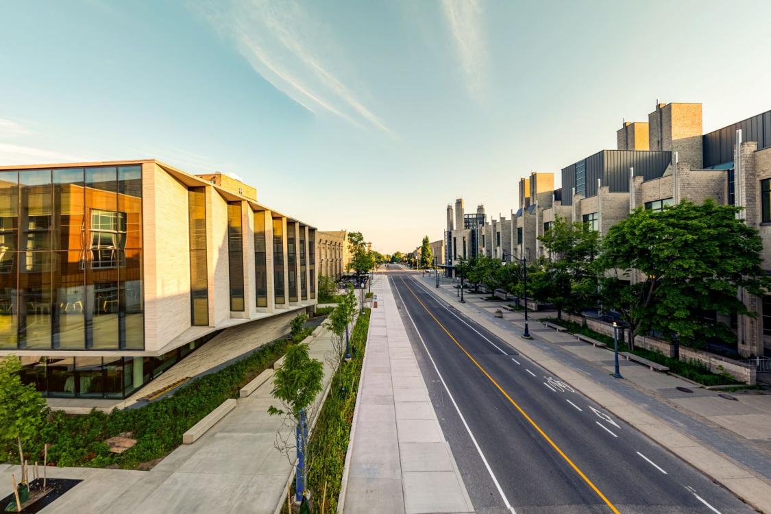 A road with building on either side, with the sun cast upon them.
