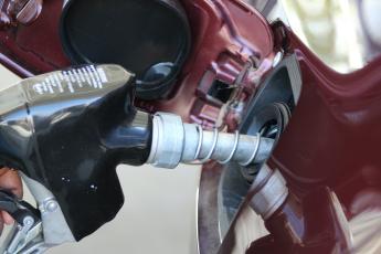 A gas pump nozzle is inserted into a car's gas tank.