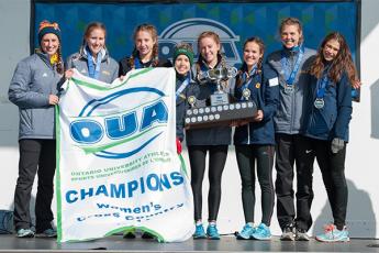 "Women's cross country team holds up OUA banner"