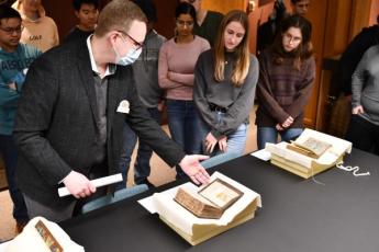 Curator Brendan Edwards displays a rare, ancient book to some of the Schulich Leaders.