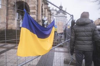 A Ukraine flag hangs on a fence outside a building.