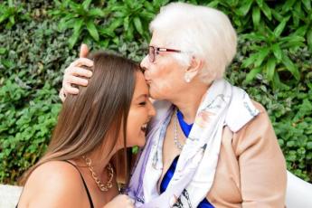 A grandmother kisses the forehead of her granddaughter