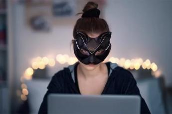 A woman wears a mask around her eyes as she looks at a computer