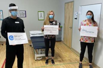 School of Rehabilitation Therapy students hold up signs on the partners for Rehabilitation Services at the Health Hub