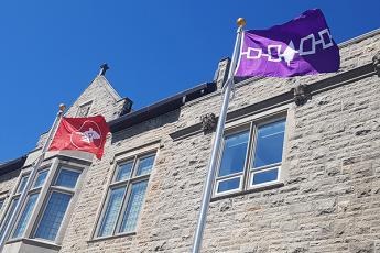 Anishinaabek and Haudenosaunee flags flying in front of Richardson Hall
