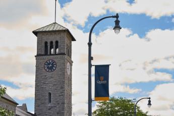 A blue Queen's pole banner in front of Grant Hall 