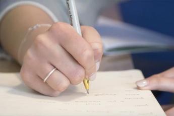 A young woman writes in a notebook with a Sharpie