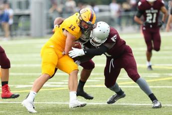 "Jonah Pataki of the Queen's Gaels is tackled by a pair of Ottawa Gee-Gees players."