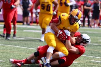"A Queen's Gaels football plyer is tackled by a member of the Carleton Ravens"