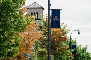 A blue Queen's pole banner is displayed in front of Grant Hall.