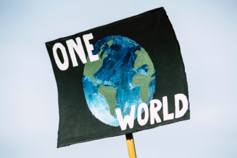 A sign featuring the earth and the text "One World"