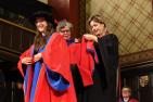 Doctoral graduate is hooded by two professors 