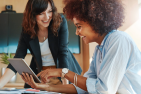 two women laughing over a computer