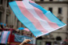 A trans pride flag being waved in the air
