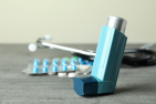 Blue medica inhaler on a desk with pills in the background