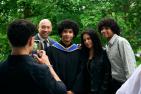 Family of four posing, one of which is a graduate, getting their photo taken.