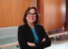 Woman in black blazer and blue shirt smiling