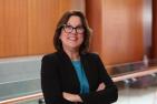Woman in black blazer and blue shirt smiling