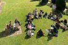 Students sitting in a circle on a green lawn.