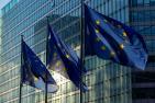 European Union flags in front of glass building.