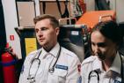Two paramedics sitting in the ambulance looking defeated.