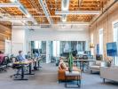 An office workspace with desk and brown leather couch. 
