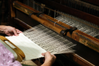 Elderly persons hands holding the threads of a loom