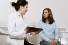 Woman speaking to a doctor holding a tablet.