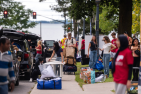 New students and volunteers helping students move into a residence building, with the lake in the background.