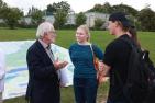 An older man talking to two university-aged students outside.