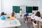 Teacher pointing to map in classroom with children.`