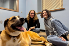 a dog and two women sitting on the ground. 