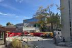 Fenced-in construction, surrounded by buildings.