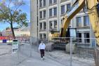 Woman walking through construction, with metal fences on either side of her.