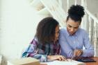 A mother and a daughter doing homework at the dining table, happy.