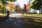 [Photo of someone riding a bike through Queen's campus]