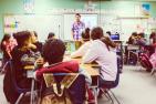 A teacher leads middle school-aged students in a classroom
