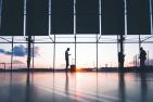 Three people stand in front of a window at an airport