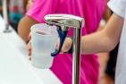 Children fill a plastic cup with water from a tap.