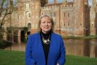 [Janine Griffiths-Baker in front of Herstmonceux Castle wearing a blue blazer ]