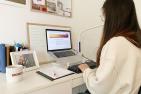 A female student works on her laptop on a desk at her home.