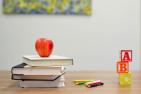 teacher's desk with an apple, books and letter blocks