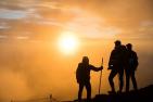 Hikers on a hillside watching the sun rise.