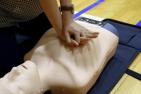 [Photo of a person practicing CPR on a training dummy]