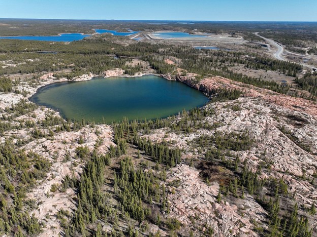 Aerial view of Pocket Lake catchment showing a blue lake with a green moat, a primarily bedrock surrounding (pink granite dominated) with sparse pine trees