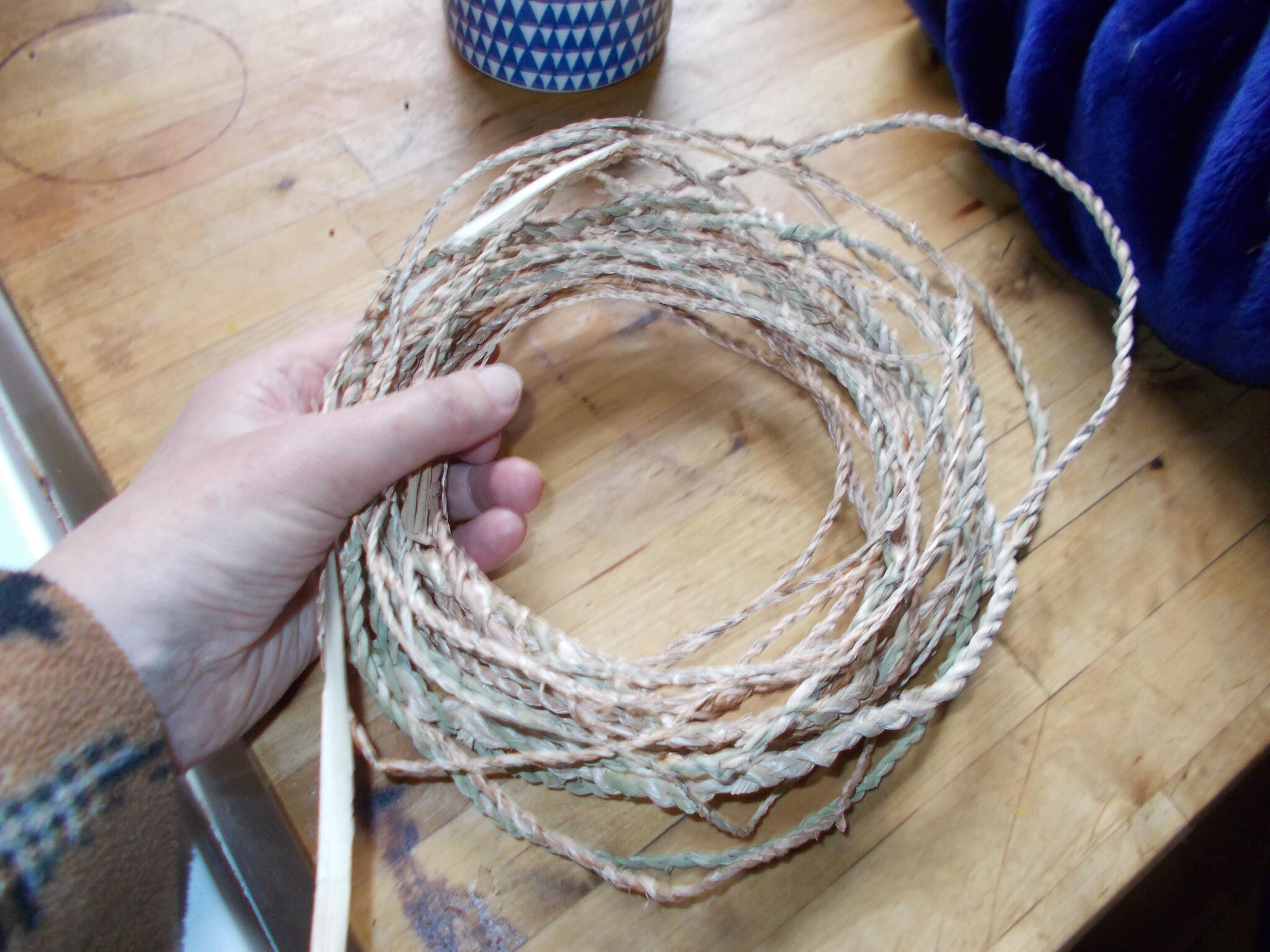 Hand holding loop of twine made with cattail fibres