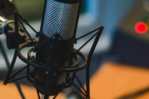 Wired boom microphone mounted to desk with background equipment