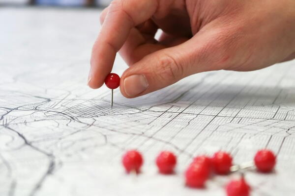A person places red push pins in a map.